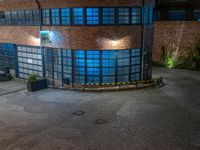 some dark blue windows in an industrial building with no one on the street to the right