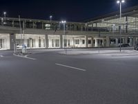 an empty parking lot near some building at night with streetlights shining down on it