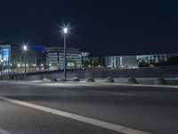 large building on the street with lights in front and other buildings nearby at night with no one moving