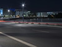 large building on the street with lights in front and other buildings nearby at night with no one moving