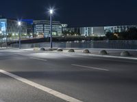 large building on the street with lights in front and other buildings nearby at night with no one moving