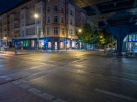 the empty street is filled with people walking and biking under an overpass at night