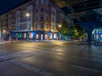 the empty street is filled with people walking and biking under an overpass at night