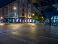 the empty street is filled with people walking and biking under an overpass at night