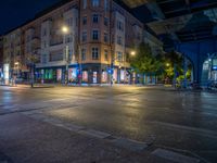 the empty street is filled with people walking and biking under an overpass at night