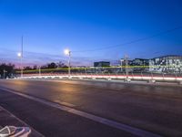 long exposure photograph of a traffic light crossing the street at twilight time with buildings and high - rise office in the distance