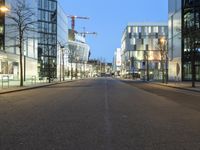 a paved street in the middle of buildings with tall windows at night, with car lights on