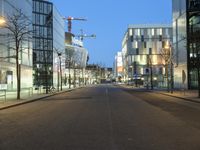 a paved street in the middle of buildings with tall windows at night, with car lights on