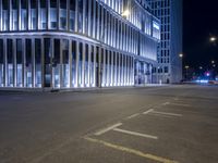 an empty street in front of a modern building on a city street at night time