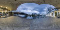 a fish eye image of a pedestrian tunnel and a walkway and stairs that is reflecting the water in the distance