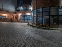 some dark blue windows in an industrial building with no one on the street to the right