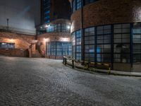 some dark blue windows in an industrial building with no one on the street to the right