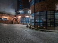 some dark blue windows in an industrial building with no one on the street to the right