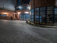 some dark blue windows in an industrial building with no one on the street to the right