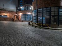 some dark blue windows in an industrial building with no one on the street to the right