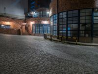 some dark blue windows in an industrial building with no one on the street to the right