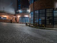 some dark blue windows in an industrial building with no one on the street to the right