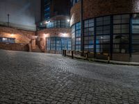 some dark blue windows in an industrial building with no one on the street to the right