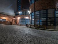 some dark blue windows in an industrial building with no one on the street to the right