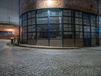 some dark blue windows in an industrial building with no one on the street to the right