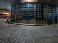 some dark blue windows in an industrial building with no one on the street to the right