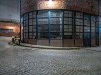 some dark blue windows in an industrial building with no one on the street to the right