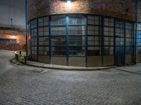 some dark blue windows in an industrial building with no one on the street to the right