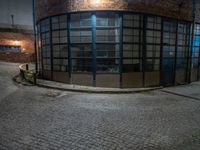 some dark blue windows in an industrial building with no one on the street to the right