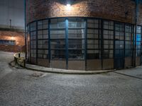 some dark blue windows in an industrial building with no one on the street to the right