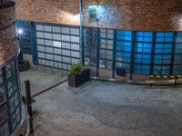 some dark blue windows in an industrial building with no one on the street to the right