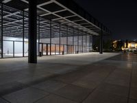 a view of the inside of a large building at night, from across the sidewalk