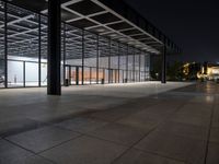 a view of the inside of a large building at night, from across the sidewalk