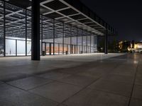 a view of the inside of a large building at night, from across the sidewalk