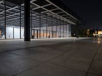 a view of the inside of a large building at night, from across the sidewalk