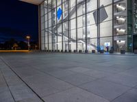 a very big square with some stairs and windows at night time with a fire hydrant sitting in front of it