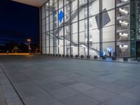 a very big square with some stairs and windows at night time with a fire hydrant sitting in front of it