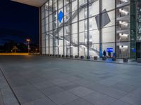 a very big square with some stairs and windows at night time with a fire hydrant sitting in front of it