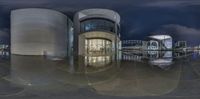 the reflection of two buildings at night on water surface in circular sphere shot, with bright lights reflecting onto the building exterior,