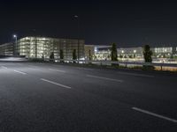 empty street with buildings and lights in the background at night time on street near the highway