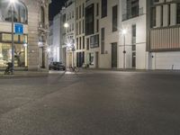 a empty street at night with two parked bicycles in the background near a store front