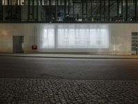 a brick sidewalk near an office building and street light at night / with a white screen over the windows