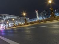 a road with lights shines in the dark over an empty street at night near a city