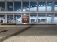 an empty street in front of the doors of a building at night with sunlight shining