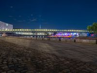 the walkway is next to the river with several boats on it in front of buildings