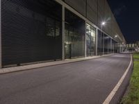 an empty road in front of a factory that is being turned into a parking lot at night