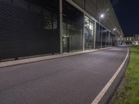 an empty road in front of a factory that is being turned into a parking lot at night