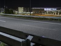 a bench sitting next to the side of a road in an empty parking lot at night