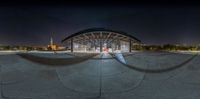 a fisheye view of the night skyline from a skateboard park with a man