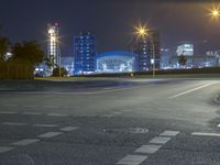 a empty street has light posts at night next to buildings and roads on both sides