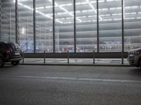 some cars and some buildings at night in a city street by windows at a parking structure